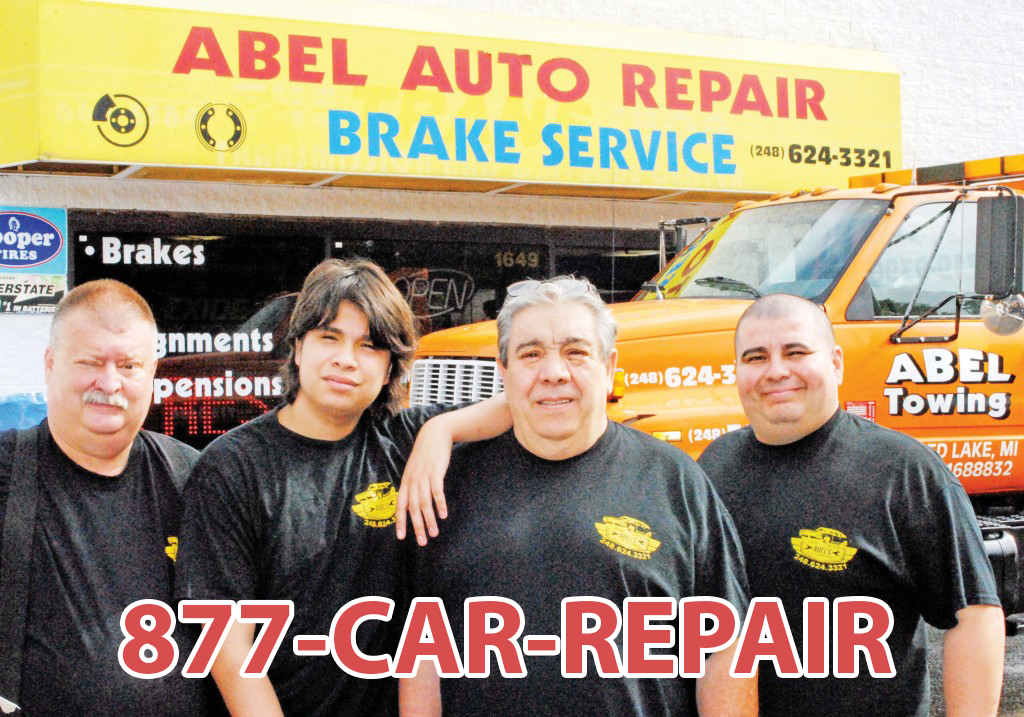 Four guys standing in front of a car repair shop using 1-877-CAR-REPAIR